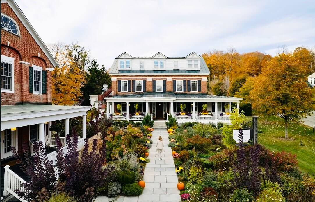 Large Two story Brick House with Wraparound Porch Autumn Garden and Pumpkins Lining a Stone Walkway Leading to the Entrance