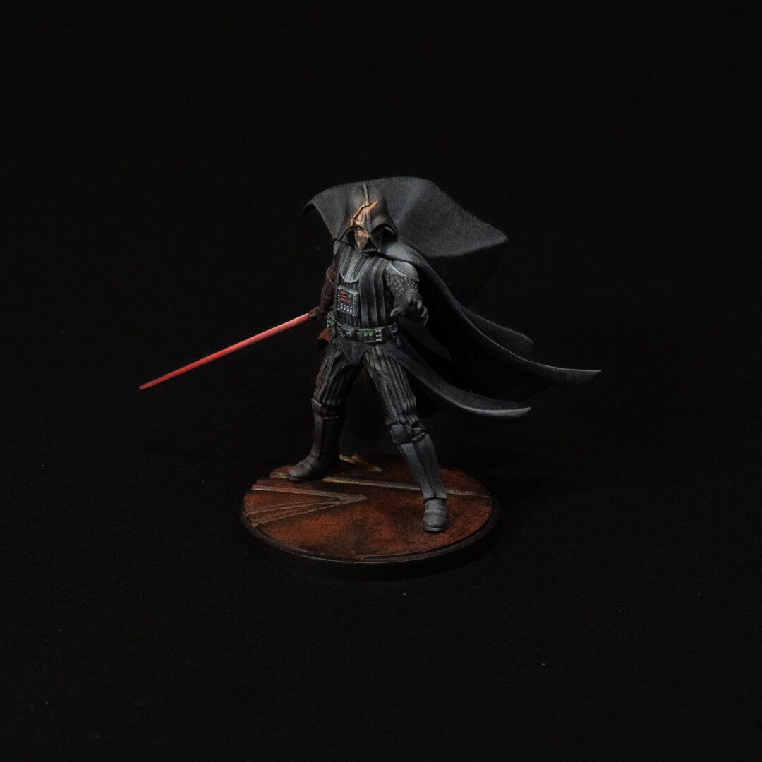 Darth Vader Action Figure Standing with a Red Lightsaber Drawn Cape Flowing on a Round Brown Base