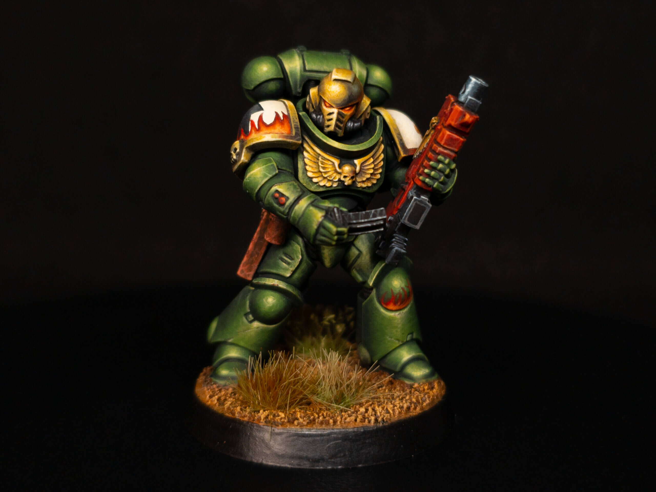 Fundamentals Wicked Dicey Green Space Marine Miniature in Ornate Armor Holding a Red Weapon with a Skull Emblem on the Chest Standing on a Grassy Base