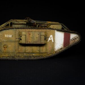 Side view of a weathered olive-drab tank model with riveted armor, showing white number 9260 and a white panel marked 'A' with a maroon stripe, set against a black background.