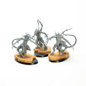 Three gray fantasy demon miniatures with long tails and spiked limbs on cork-textured bases.