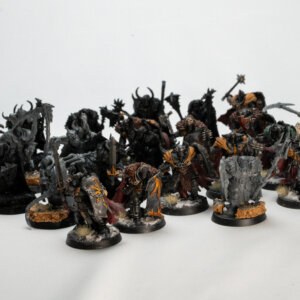 Group of dark armored fantasy miniatures arranged as a tabletop army on round bases with orange accents on the cloaks and bases with sand textures.